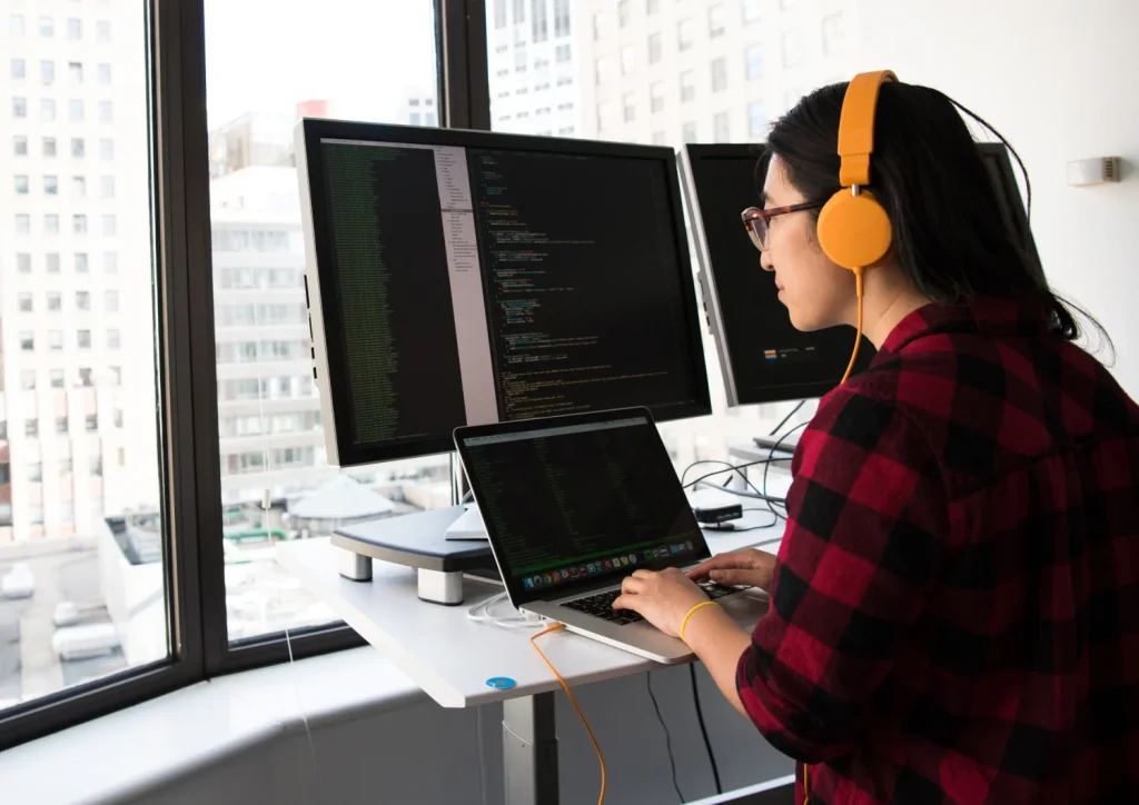 A woman with headphones on using her laptop.