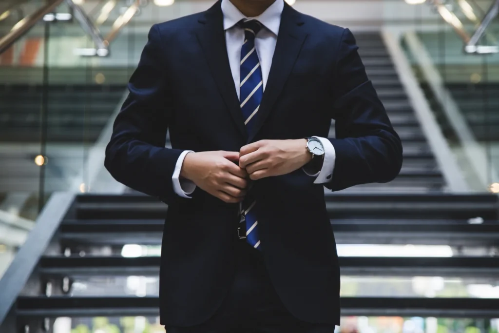 A man in a suit and tie standing next to stairs.