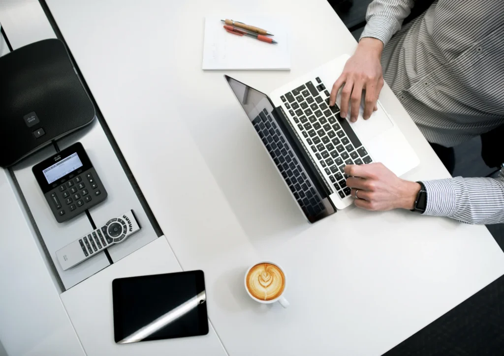 A person sitting at a desk with two laptops.